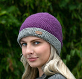 A woman wearing a purple crochet turn up hat with a gray brim.